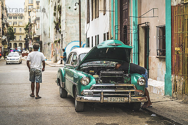 Einheimischer repariert seinen kaputten amerikanischen Oldtimer  La Habana (Havanna)  Kuba  Westindien  Karibik  Mittelamerika