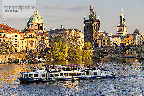 Touristenboot  das die Karlsbrücke und den Altstädter Brückenturm auf der Moldau passiert  Prag  Böhmen  Tschechische Republik  Europa