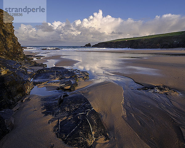 Atlantische Wolken reflektieren das Licht der Morgendämmerung auf den nassen Sand und die Felsen von Trevone in der Nähe von Padstow  Cornwall  England  Vereinigtes Königreich  Europa