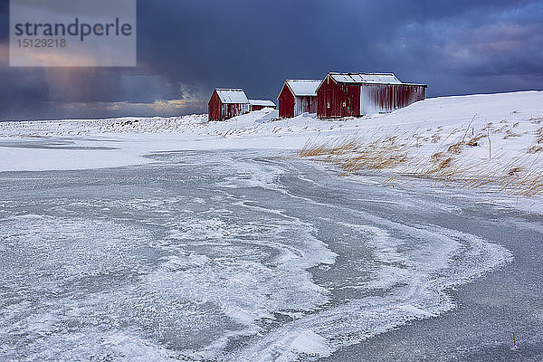 Dramatischer Himmel über typischen Fischerhäusern namens Rorbu im Winter  Eggum  Lofoten  Arktis  Norwegen  Europa