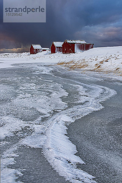 Typische Fischerhäuser Eisformationen mit dramatischem Himmel im Winter  Eggum  Lofoten Inseln  Arktis  Norwegen  Europa