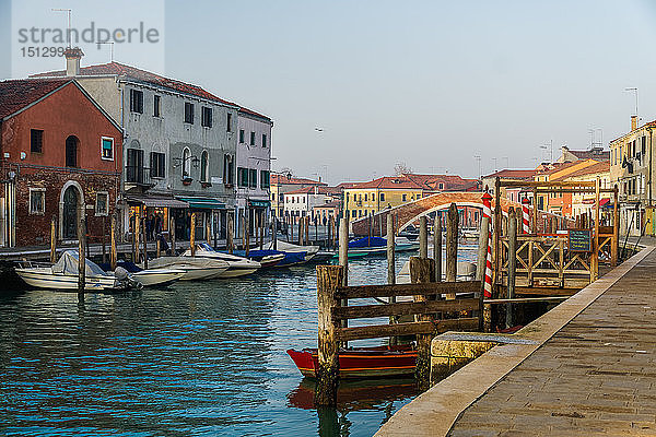 Blick auf die Steinbrücke Ponte San Martino über den Kanal mit bunten Gebäuden und vertäuten Booten auf hölzernen Anlegestellen  Murano  Venedig  UNESCO-Weltkulturerbe  Venetien  Italien  Europa