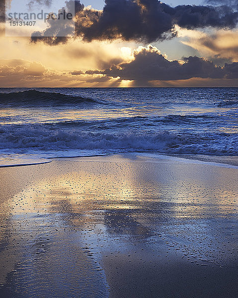 Frühmorgendliches Licht glitzert auf dem nassen Sand mit dramatischen Wolken dahinter  Porthcurno  Cornwall  England  Vereinigtes Königreich  Europa