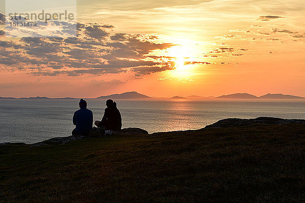 Zwei Touristen genießen einen wunderschönen Sonnenuntergang am Neist Point auf der Isle of Skye  Innere Hebriden  Schottland  Vereinigtes Königreich  Europa