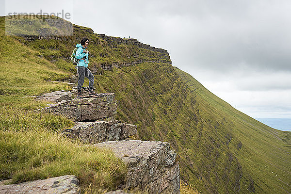 Eine Frau blickt bei einer Wanderung im Brecon Beacons National Park  Wales  Vereinigtes Königreich  Europa  von einem hohen Steilhang aus.