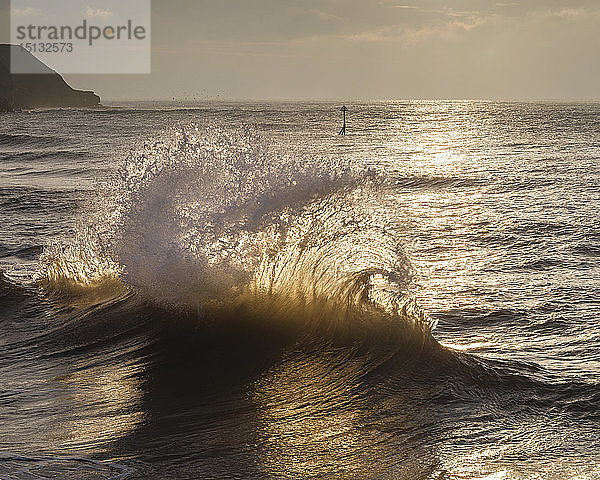 Von der Morgensonne beleuchtete Wellen  die von der Ufermauer reflektiert werden und mit einer ankommenden Welle zusammenstoßen  Exmouth  Devon  England  Vereinigtes Königreich  Europa