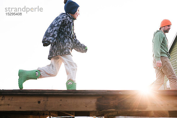 Junge mit Vater läuft über die sonnenbeschienene Skateboard-Rampe  Blickwinkel niedrig