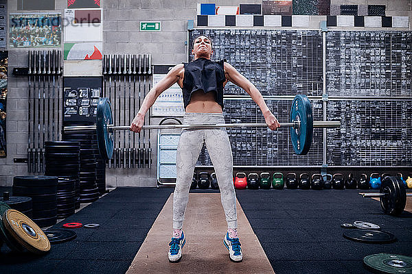 Junge Frau hebt Langhantel im Fitnessstudio