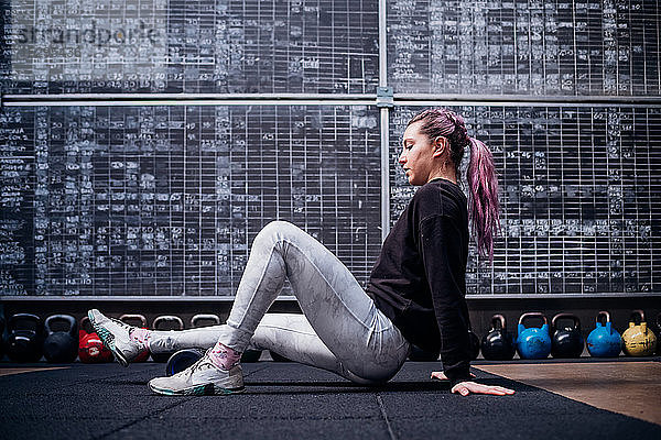 Junge Frau massiert Wade mit Schaumstoffrolle im Fitnessstudio