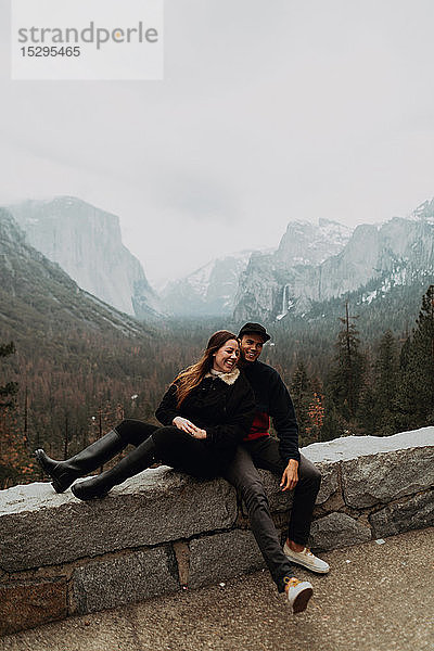Glückliches junges Paar sitzt auf einer Mauer in einer Berglandschaft  Yosemite Village  Kalifornien  USA