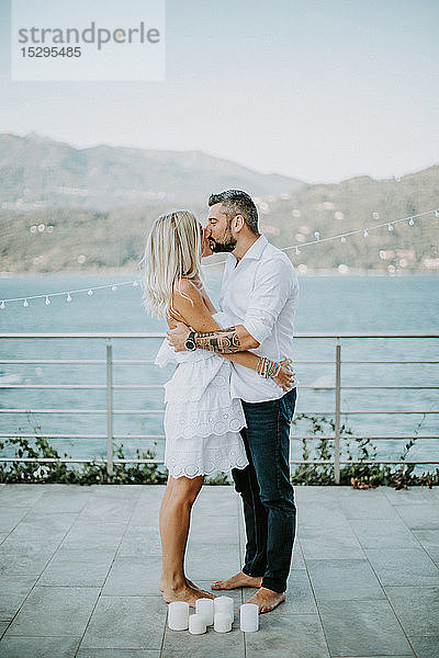 Romantisches Paar mittlerer Erwachsener küsst sich am Seeufer  Stresa  Piemont  Italien