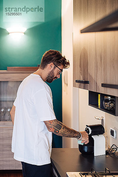 Mittelgroßer Erwachsener  der Kaffee aus der Kaffeemaschine auf die Küchentheke gießt