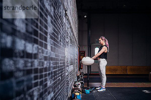 Junge Frau pudert sich im Fitnessstudio die Handflächen