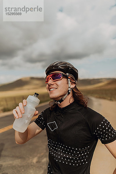 Junger männlicher Radfahrer mit einer Wasserflasche in der Hand auf einer Landstraße  Exeter  Kalifornien  USA