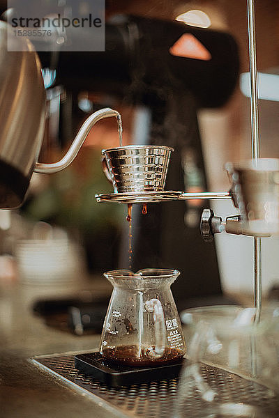 Gekochtes Kesselwasser  das in den Kaffeefilter läuft und in die Kanne auf der Kaffeetheke tropft  flacher Fokus