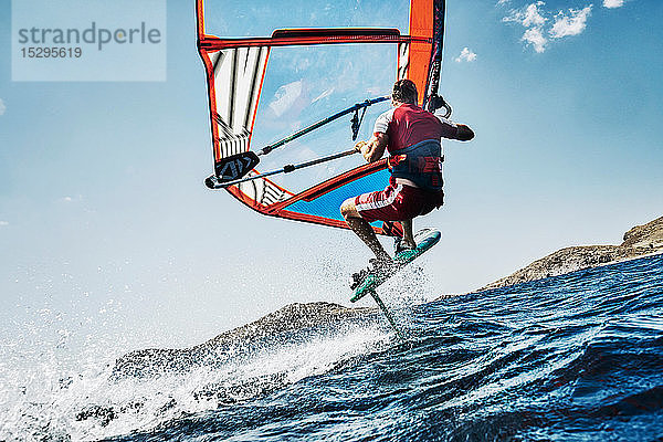 Junger Mann in der Luft beim Windsurfen auf Meereswellen  Seitenansicht  Limnos  Khios  Griechenland