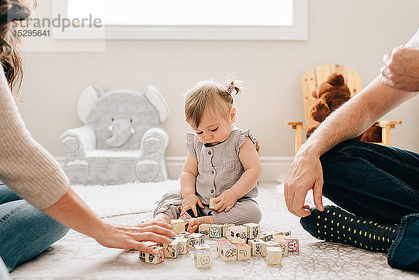 Mutter und Vater auf der Kindertagesstätte  während die kleine Tochter mit Bauklötzen spielt  ausgeschnitten