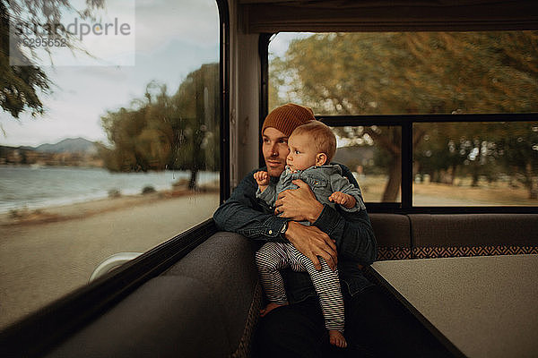 Vater und Baby schauen aus dem Fenster eines Wohnmobils  Wanaka  Taranaki  Neuseeland