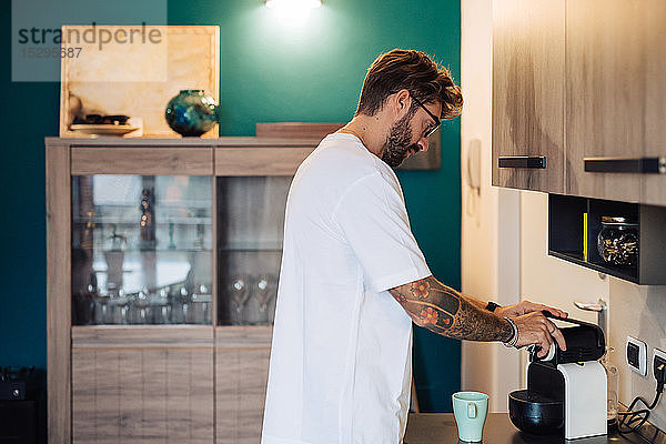 Mittelgroßer erwachsener Mann bereitet Kaffeemaschine auf der Küchentheke vor