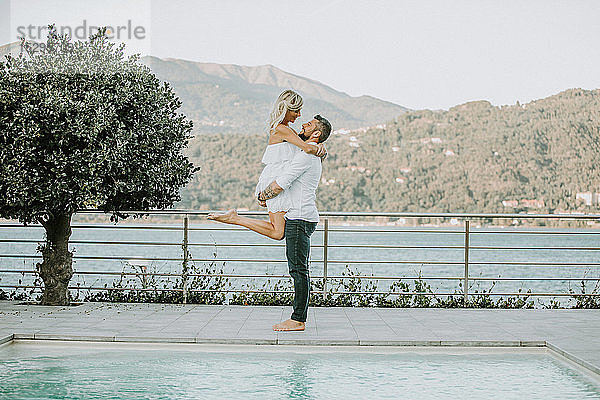 Romantischer mittelgroßer Mann  der seine Freundin am Pool hochhebt  Porträt  Stresa  Piemont  Italien