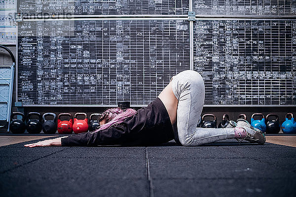 Junge Frau beim Stretching des Oberkörpers im Fitnessstudio