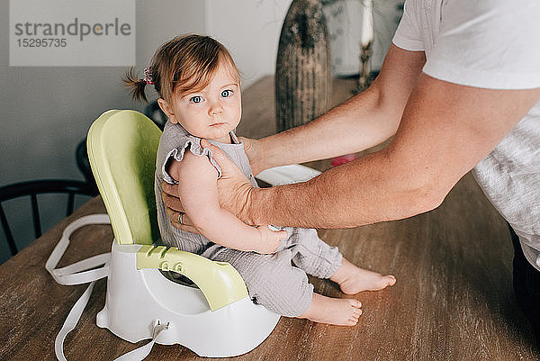 Vater setzt Tochter in Kindersitz  Portrait beschnitten