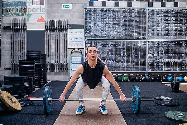 Junge Frau hebt Langhantel im Fitnessstudio