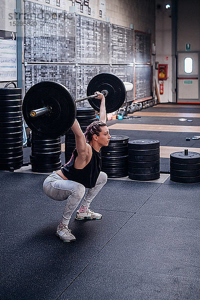 Junge Frau hebt Langhantel im Fitnessstudio