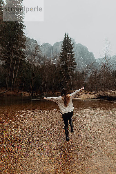 Junge Frau springt in Flussniederungen  Rückansicht  Yosemite Village  Kalifornien  USA