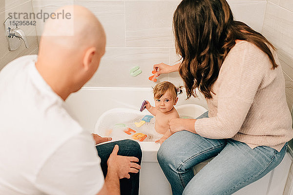 Mutter und Vater spielen mit der kleinen Tochter in der Badewanne  Blick über die Schulter