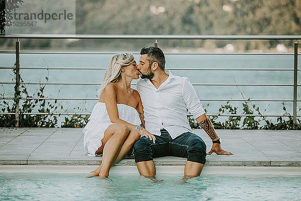 Romantisches Paar mittlerer Erwachsener  die sich am Pool küssen  Stresa  Piemont  Italien