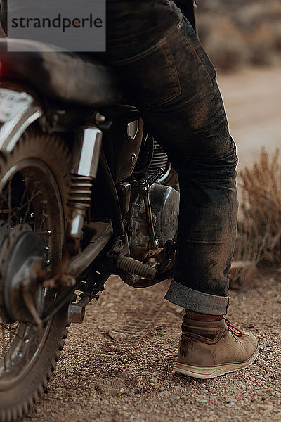 Gestiefeltes Bein eines Mannes auf Motorrad