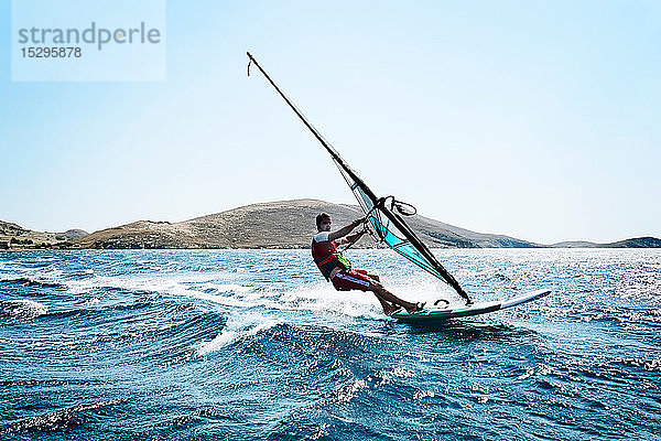 Junger Mann beim Windsurfen auf Meereswellen  Seitenansicht  Limnos  Khios  Griechenland