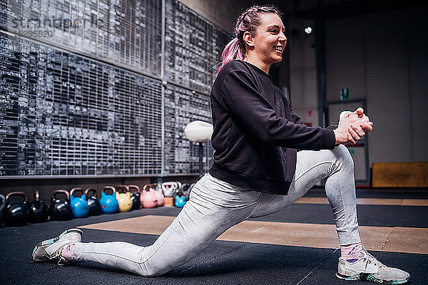 Junge Frau beim Stretching der Beine im Fitnessstudio