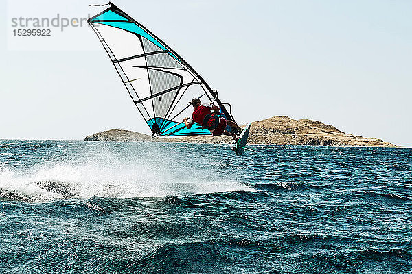 Junger Mann beim Windsurfen über der Meereswelle  Rückansicht  Limnos  Khios  Griechenland