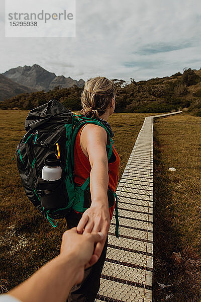 Wanderer hält die Hand eines Freundes auf einem Wanderweg  Queenstown  Canterbury  Neuseeland
