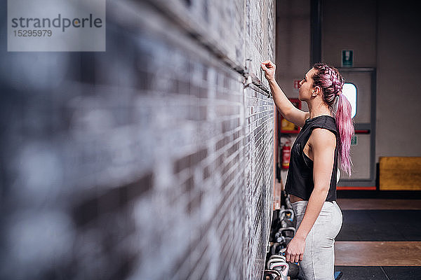 Junge Frau schreibt im Fitnessstudio auf die Anzeigetafel