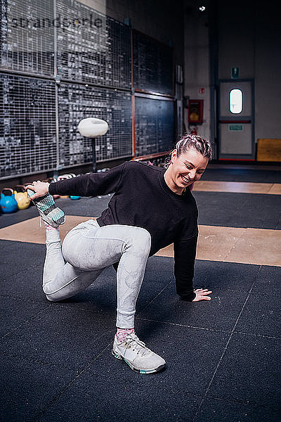 Junge Frau beim Stretching der Beine im Fitnessstudio