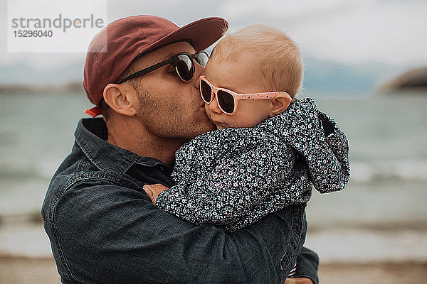 Vater küsst Baby am Strand