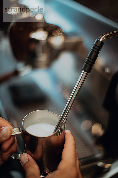 Barista erwärmt Milchkännchen auf der Kaffeemaschine im Café  Nahaufnahme