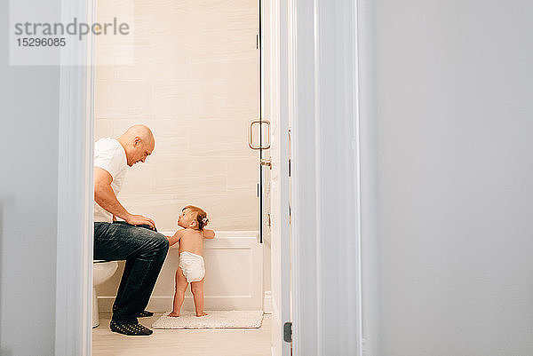 Vater mit Baby-Tochter bereitet Bad vor