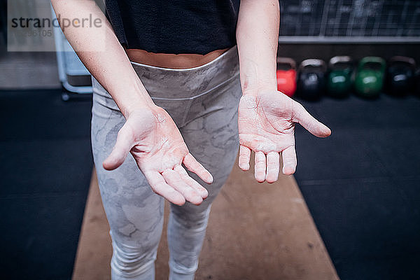 Junge Frau mit Schwielen auf Handflächen im Fitnessstudio