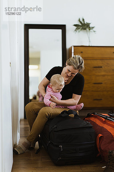 Mutter im Gepäck mit Baby im Schlafzimmer