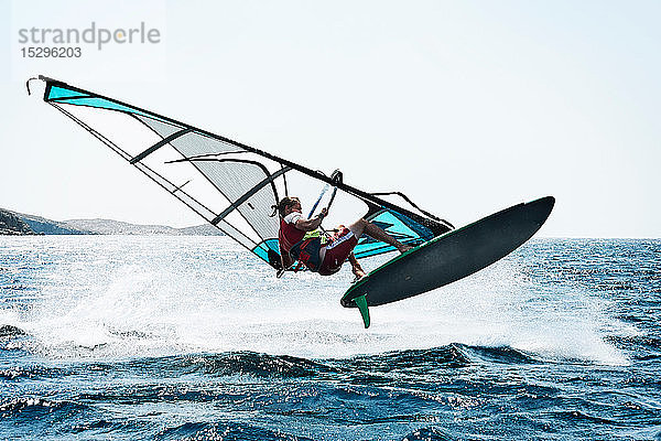 Junger Mann beim Windsurfen über den Wellen des Ozeans  Limnos  Khios  Griechenland