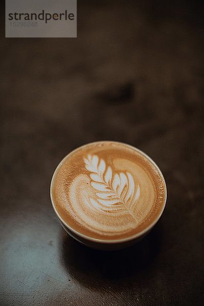 Tasse Milchkaffee mit Blattmuster auf Café-Theke  Draufsicht