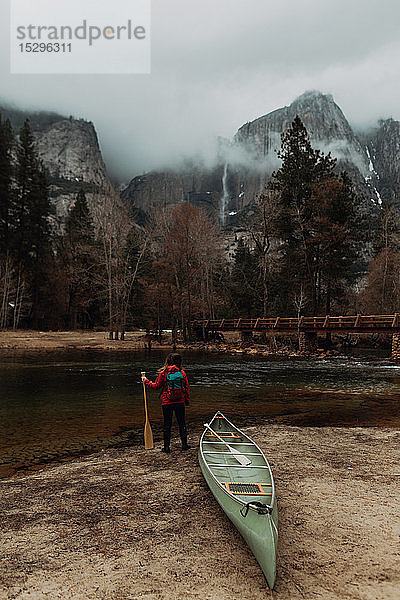 Junge Kanufahrerin schaut vom Flussufer aus  Rückansicht  Yosemite Village  Kalifornien  USA