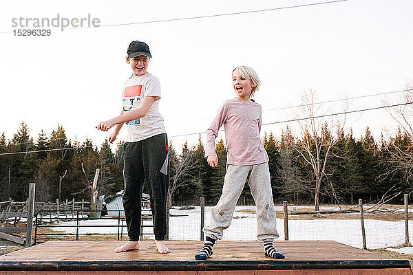 Junge und Schwester tanzen auf einer ländlichen Betonplatte