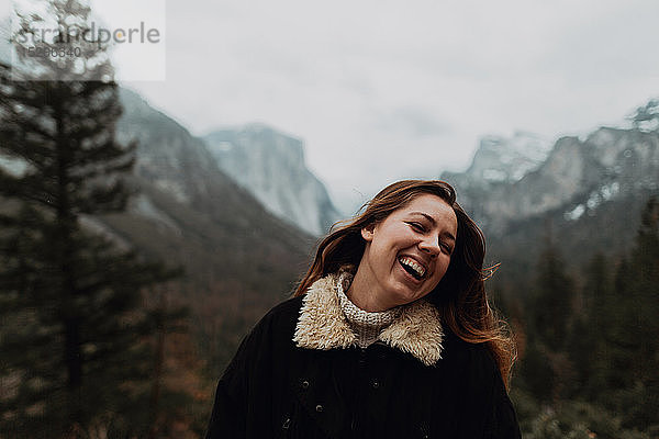 Junge Frau lacht in Berglandschaft  Kopf und Schultern  Yosemite Village  Kalifornien  USA
