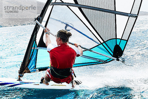 Junger Mann beim Windsurfen auf der Meereswelle  Rückansicht  Limnos  Khios  Griechenland