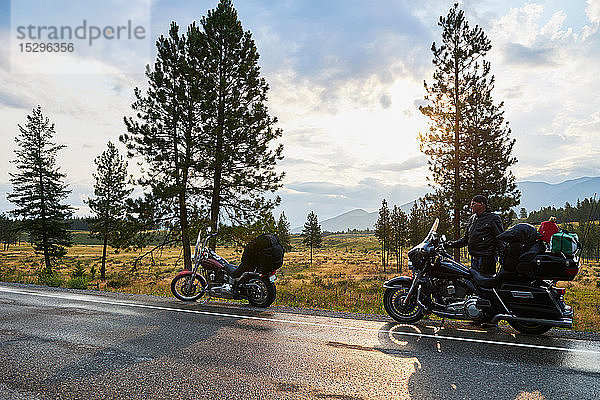 Älterer männlicher Motorradfahrer mit Motorrad am ländlichen Straßenrand  Dawson Creek  Kanada